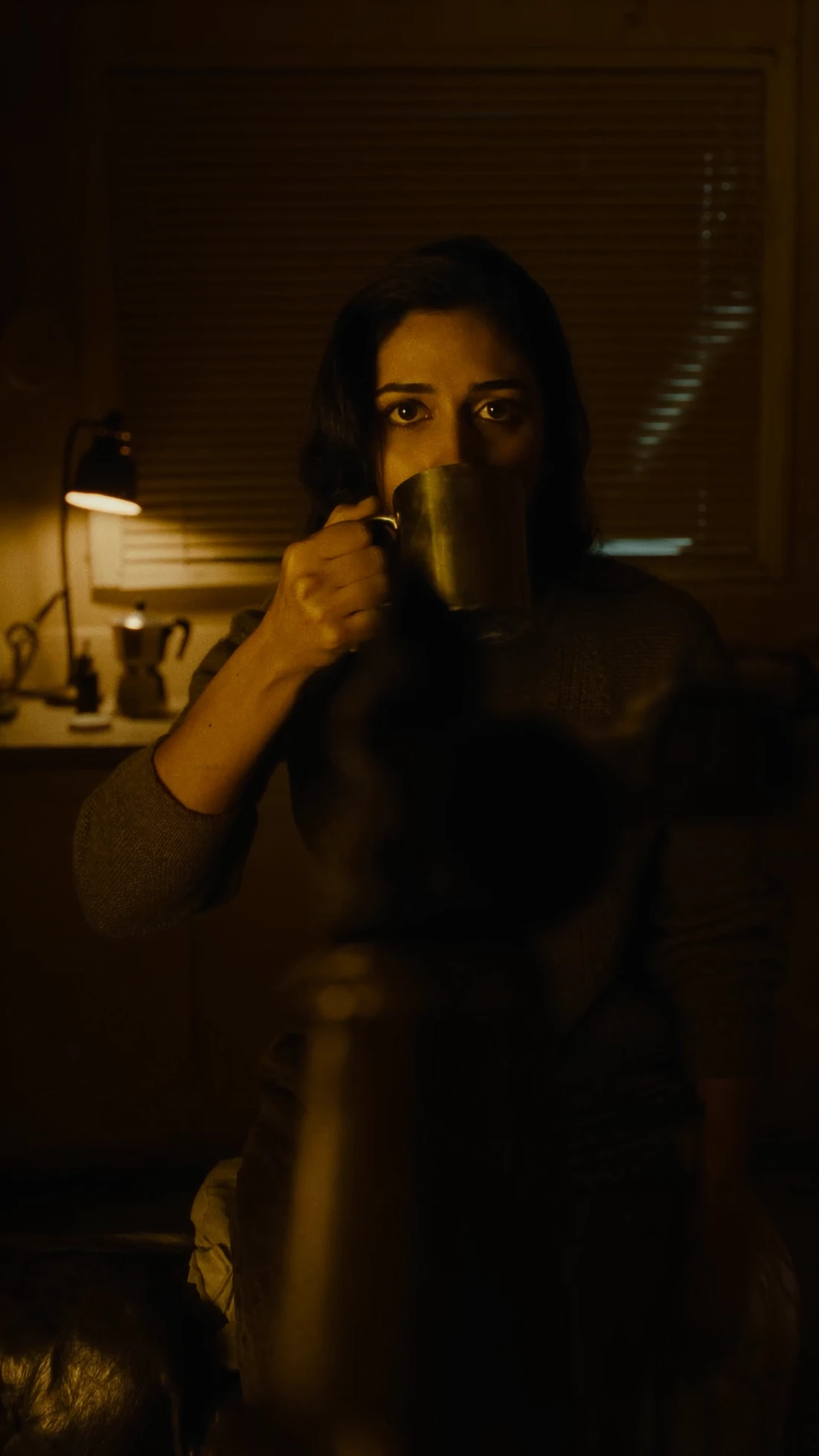 Still from an AI-generated short film: a woman lit by a single lamp in a night interior