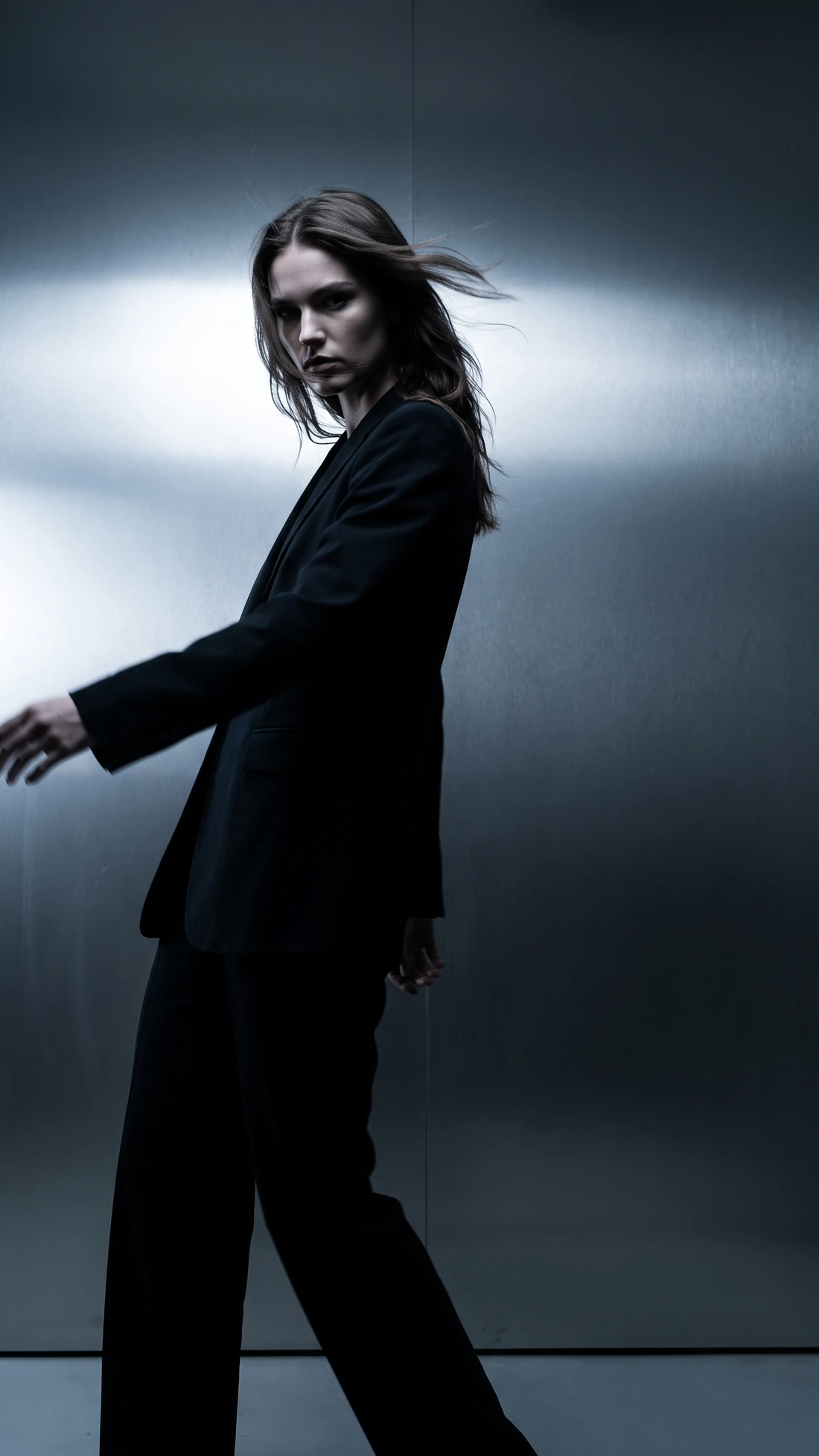 Brand film still: a figure in a black suit against brushed metal
